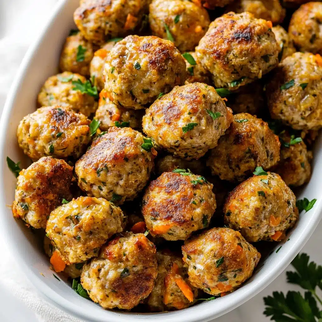 Turkey Stuffing Balls, leftover turkey appetizers, savory stuffing bites, comfort food finger foods, holiday turkey snacks The image shows a white bowl full of round golden-brown meatballs with a slightly crispy texture on the outside. Each meatball is lightly speckled with small pieces of herbs and seasoning, giving them a dotted green and orange look. Some meatballs have small browned spots, showing they are cooked well. Small fresh green parsley leaves are scattered on top and inside the bowl, adding a fresh contrast to the warm colors. The bowl sits on a white marbled surface with a soft grey cloth partially under it.