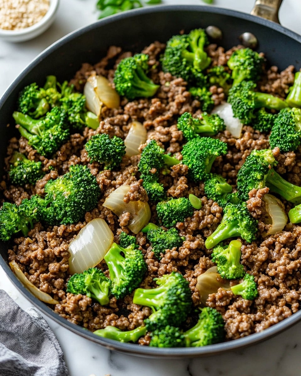 Ground Beef and Broccoli Stir Fry, quick beef broccoli stir fry, healthy ground beef recipes, easy beef stir fry dinner, 30-minute beef broccoli dish The image shows a white speckled bowl filled with three main layers: the bottom layer is light brown fried rice, fluffy with separate grains; the middle layer contains bright green broccoli florets and slices of vibrant red bell pepper, mixed through the rice; the top layer features small, dark brown pieces of cooked ground meat coated with a glossy sauce and sprinkled with white sesame seeds and chopped green onions, adding texture and color. The bowl sits on a white marbled surface, with a white cloth napkin at one side and a small white bowl of sesame seeds in the background,