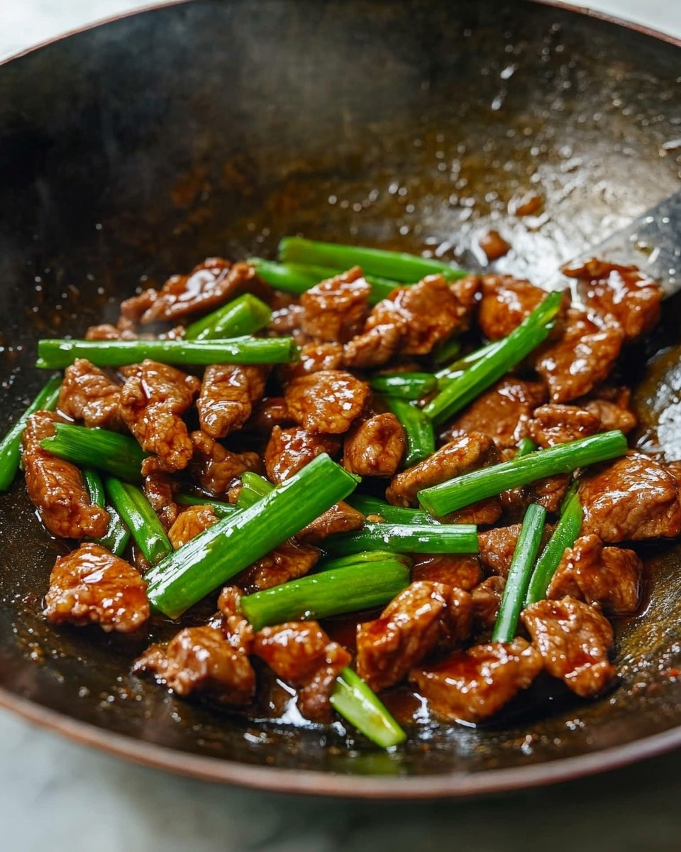 The image shows a dark metal wok filled with rich brown cooked chicken pieces mixed with bright green chopped scallions. The chicken has a shiny, slightly sticky texture from the sauce, and the scallions are fresh and crisp. The wok sits on a stove, with some glistening oil and sauce pooling at the bottom, giving a warm and tasty look. The background is a white marbled texture. photo taken with an iphone --ar 4:5 --v 6.1