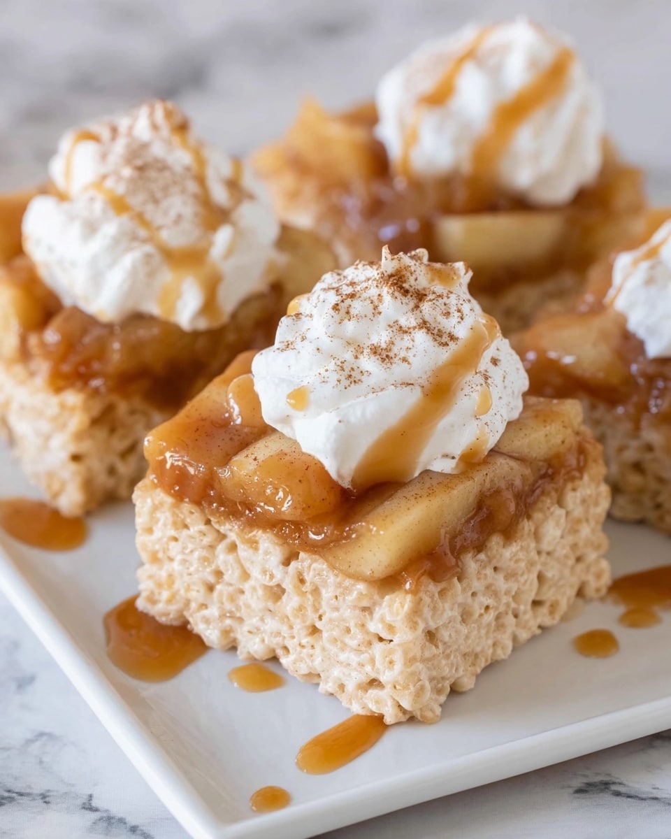 The dish shows squares of light golden crispy rice treats on a white plate, each topped with a glossy layer of caramelized apple mixture in a caramel brown color, giving a shiny and slightly chunky texture. On top of the apple layer, there is a dollop of fluffy white whipped cream dusted with a light sprinkle of cinnamon powder. A drizzle of golden caramel sauce runs across the treats and the white plate, which sits on a white marbled surface. photo taken with an iphone --ar 4:5 --v 7