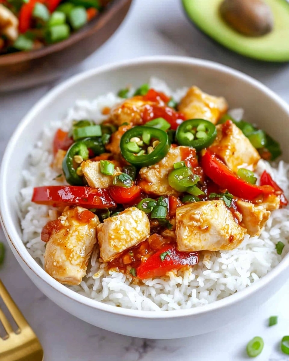 A white bowl filled with three layers: the bottom layer is soft white rice, the middle layer has bright red bell pepper strips and sliced green jalapeño peppers, and the top layer shows golden brown cooked chicken pieces with a glossy red sauce drizzled over them. There are small green onion slices scattered on top and around the dish. The bowl is placed on a white marbled surface with a wooden bowl of chopped green onions, half an avocado, and a gold fork slightly blurred in the background. Photo taken with an iphone --ar 4:5 --v 6.1