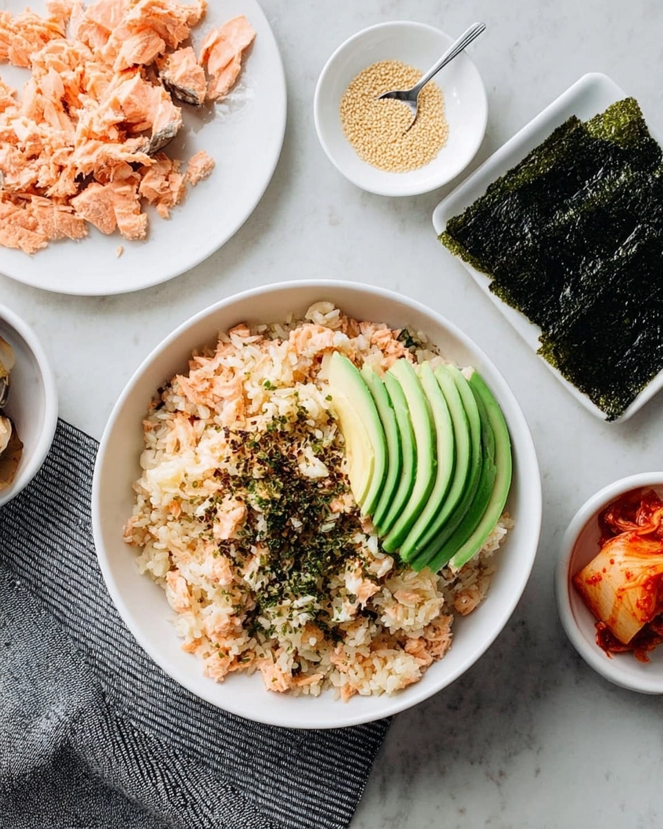 A woman's hand is holding a small stack of food layers. The bottom layer is a dark green seaweed sheet with a rough texture. On top of that is a layer of light brown rice mixed with small orange pieces, followed by a smooth, bright green slice of avocado. The top layer has some small bits of red kimchi. In the background, there is a white bowl filled with more rice and avocado slices, placed on a white marbled surface. The scene has a soft focus with natural lighting, showing a casual meal setting. photo taken with an iphone --ar 4:5 --v 7