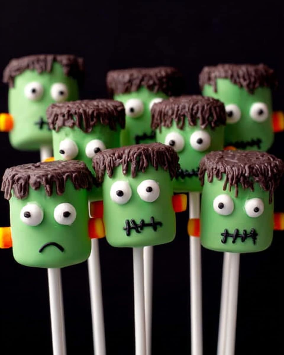 The image shows seven marshmallows on white sticks, decorated as green Frankenstein heads. Each marshmallow has a smooth green coating covering it fully, with a dripping layer of dark brown on top, resembling hair. Two round candy eyes are placed on the front of each marshmallow, with simple black zigzag lines below to represent a mouth. Red stitch marks with four lines are drawn on the green coating near the top on each one. Small brown rectangular pieces stick out from each side to look like bolts. All the marshmallows stand upright against a dark background. photo taken with an iphone --ar 4:5 --v 7