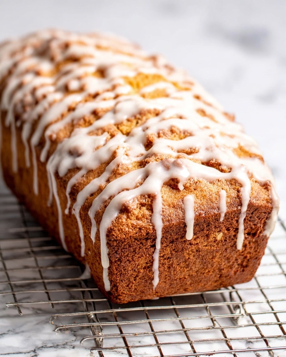 The image shows a close-up of two slices of cinnamon swirl bread on a silver cooling rack, placed over a white marbled surface. Each slice is thick with a golden brown crumb and a dark brown spiral of cinnamon running through the center, giving a marbled look. The outer edge of the bread is darker and slightly crusty, while the inside looks soft and moist. Only part of another slice is visible on the left and right edges of the frame. Photo taken with an iphone --ar 4:5 --v 7
