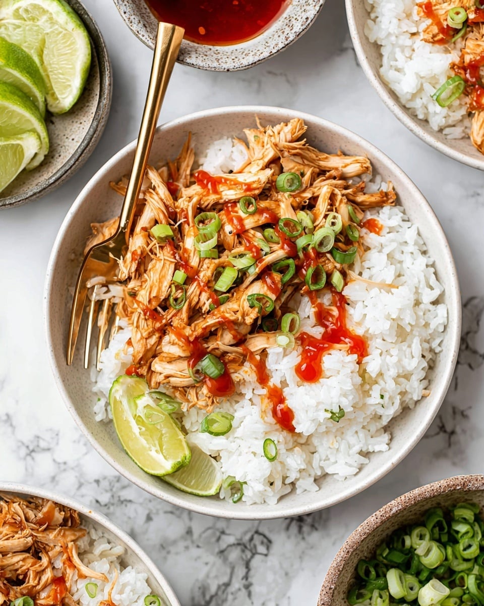 A white bowl is filled with two main layers: the bottom layer is fluffy white rice, covering half the bowl, and the top layer is shredded cooked meat in a brown sauce, spread over the rice on one side. Thin green strips of sliced green onions are scattered over the meat, with a drizzle of red sauce on top, both on the meat and partially on the rice. A gold fork rests inside the bowl on the left side, partially sticking into the meat. The bowl is set on a white marbled surface, with lime wedges and small bowls of sauce around it in the background. The photo taken with an iphone --ar 4:5 --v 7