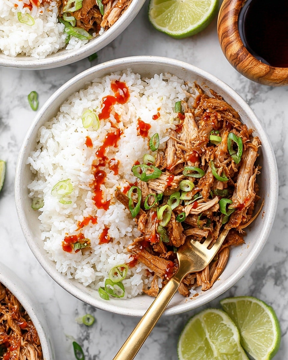 The image shows a white bowl filled halfway with fluffy white rice on one side and a layer of light brown shredded cooked meat on the other side. The meat is topped with thin, bright green slices of scallion and drizzled with a thin red sauce. A shiny gold fork rests inside the bowl, partially under the shredded meat. Around the bowl, there are lime wedges, a small bowl of additional sauce, and another white bowl with the same dish in the background, all placed on a white marbled surface. Photo taken with an iphone --ar 4:5 --v 7