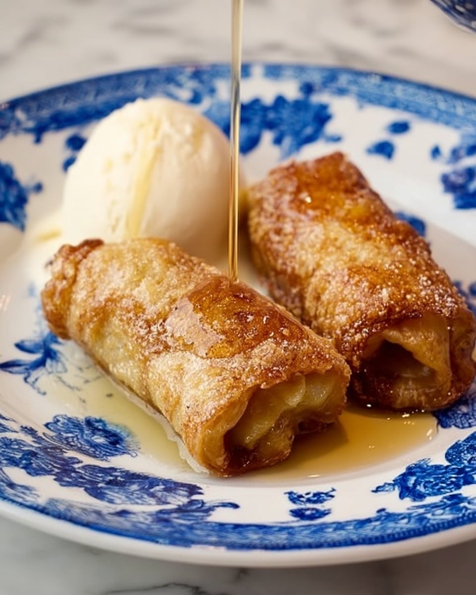 The image shows two golden brown rolled pastries with a slightly crispy, textured surface and a warm, soft filling peeking out from the ends, sitting on a white plate with blue floral patterns. Next to the pastries is a white scoop of smooth, creamy ice cream that contrasts with the warm tones of the rolls. There is a clear syrup being poured over the pastries from above, adding a shiny glaze. The plate is on a white marbled surface. Photo taken with an iphone --ar 4:5 --v 7