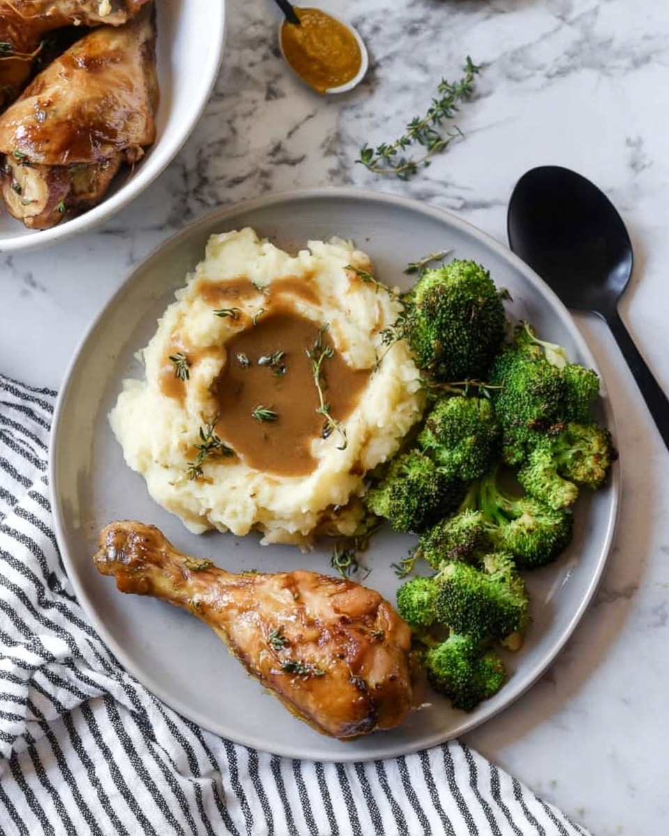 The image shows a white plate with three main sections: at the top left is a mound of creamy mashed potatoes with a smooth, slightly lumpy texture, topped with a pool of brown gravy and a sprig of green thyme. To the right of the potatoes is a small pile of bright green, soft steamed broccoli florets with a slightly shiny finish. At the bottom of the plate are two golden-brown roasted chicken drumsticks with a light herb garnish and some gravy drizzled on them. The plate sits on a white marbled surface next to a black fork and some fresh thyme sprigs with a white cloth with thin black stripes nearby. Photo taken with an iphone --ar 4:5 --v 7