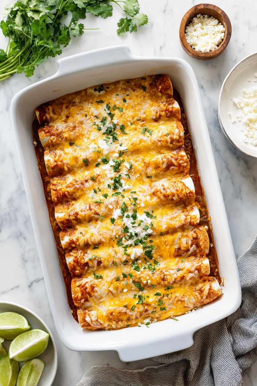 A white rectangular baking dish holds six rolled enchiladas placed side by side in one layer, covered in melted light orange cheese with slightly browned edges, and sprinkled with small green chopped herbs on top. The texture of the enchiladas looks soft and moist, with a glossy melted cheese layer that contrasts with the light green garnish. The dish is set on a white marbled surface, and a lime wedge is partially visible at the bottom left corner of the image. Photo taken with an iphone --ar 4:5 --v 7