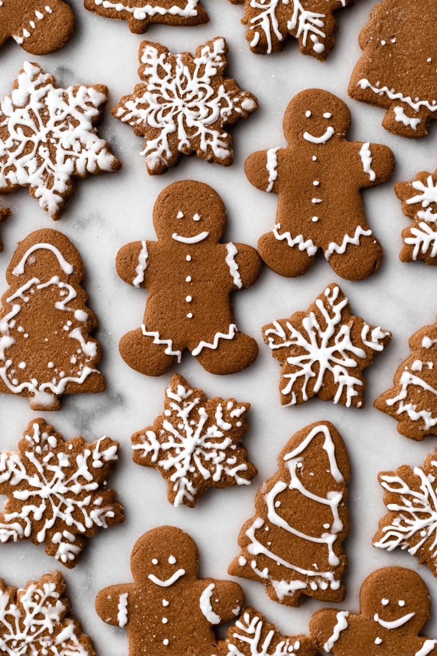 The image shows many gingerbread cookies on a white marbled surface, with different shapes like gingerbread people, snowflakes, little girls, Christmas trees, and mittens. Each cookie is brown with a slightly rough texture and decorated with white icing in patterns like snowflake details, buttons, zigzag lines, and dots. The cookies are spread out flat, overlapping slightly in some places, showing their thick yet uniform layers. The white icing adds a festive contrast to the warm brown tones of the cookies. photo taken with an iphone --ar 4:5 --v 7