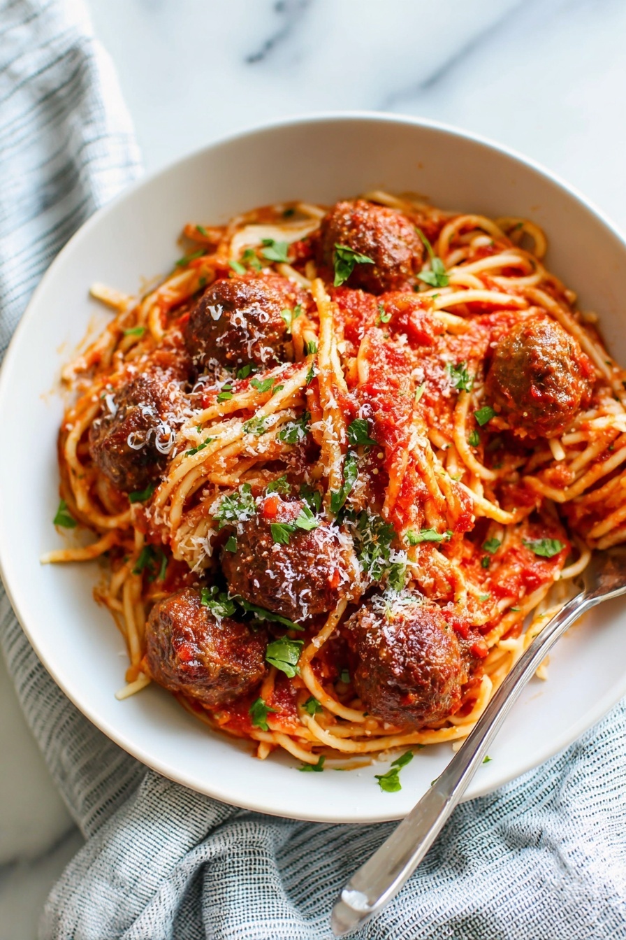 The image shows a white bowl filled with a bed of spaghetti pasta, coated in red tomato sauce with a soft texture. On top of the noodles, there are five round, brown meatballs evenly placed around the plate. The meatballs are covered with some extra tomato sauce and sprinkled with small green pieces of fresh basil and white grated cheese. A silver fork rests inside the bowl on the left side. The bowl is placed on a white marbled surface with a light blue and white striped cloth nearby. The scene is softly lit, highlighting the warm colors of the food. photo taken with an iphone --ar 4:5 --v 7