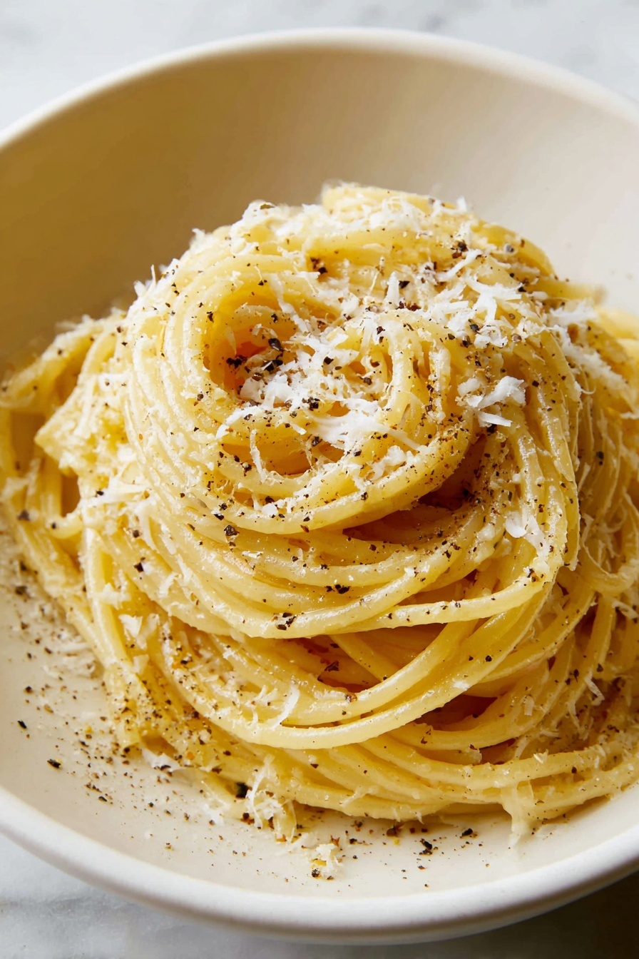A white bowl holds a mound of cooked spaghetti that is shiny with a light coating of oil and sprinkled with black pepper and grated cheese. The spaghetti strands are pale yellow with small black pepper dots and soft grated white cheese on top. A silver fork lifts a bundle of spaghetti from the bowl, showing twisted noodles with a smooth texture. In the softly blurred background, there is a small white bowl filled with more grated cheese on a white marbled surface with a textured beige cloth nearby. Photo taken with an iphone --ar 4:5 --v 7