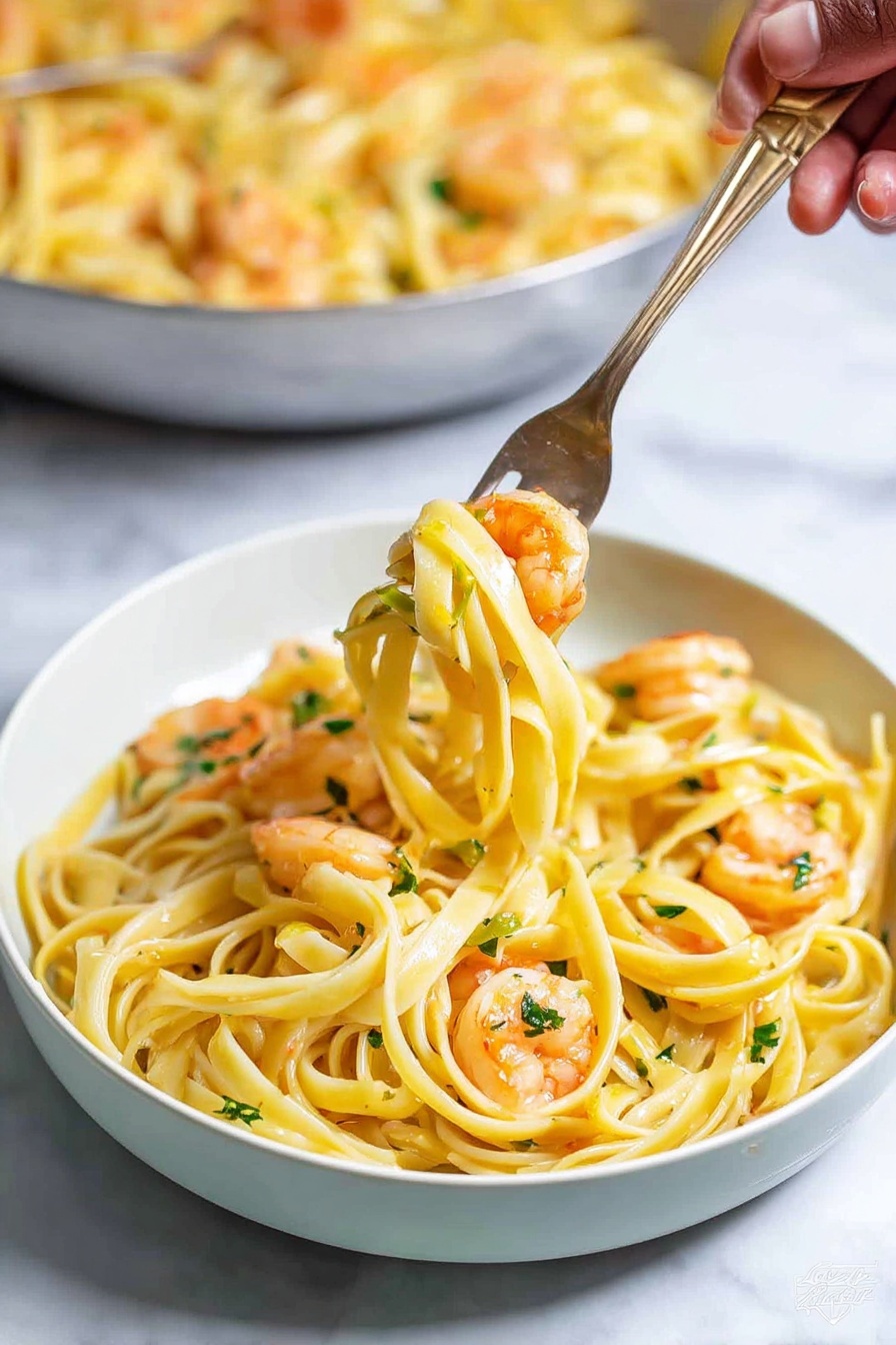 A white plate holds a serving of yellowish pasta with several small orange shrimp mixed throughout, some with light green herb bits on them. A fork lifts a small bundle of the long pasta noodles with two shrimp, showing a smooth texture on the noodles and a slight shine on the shrimp. In the background, there is a large white bowl filled with more pasta and shrimp, all set on a white marbled surface. The overall scene is brightly lit, highlighting the fresh look of the dish photo taken with an iphone --ar 4:5 --v 7