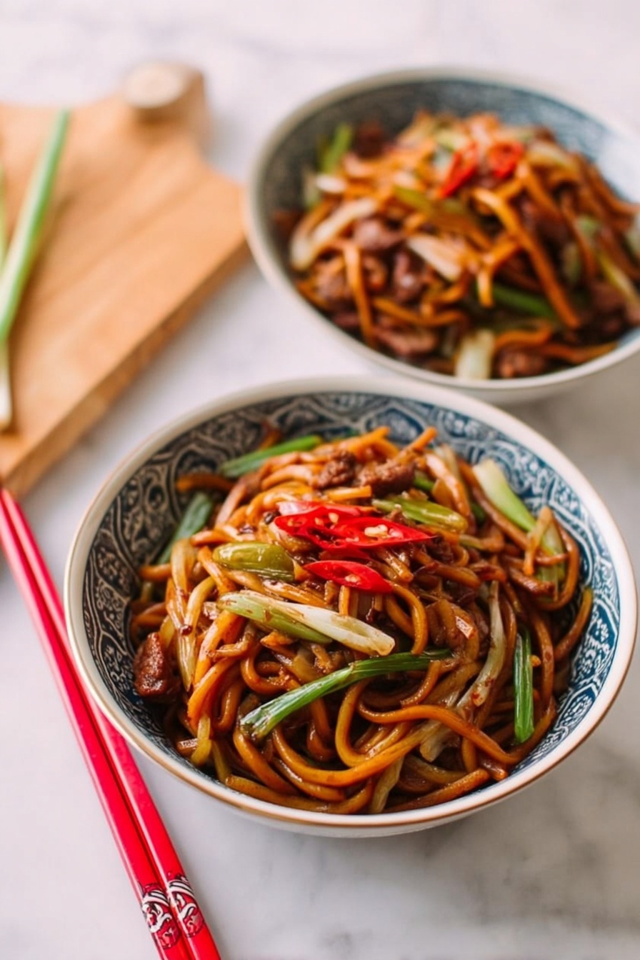 Two bowls filled with stir-fried noodles are shown on a white marbled surface. Each bowl is white with a blue patterned rim and contains thick, glossy dark orange noodles mixed with small pieces of cooked chicken and thin strips of green and white vegetables like onions and carrots. The noodles are twisted and layered throughout the bowls, with chunks of chicken resting on top and scattered inside. The bowls sit partially on a soft beige cloth that adds a warm tone to the image. A pair of red and light wooden chopsticks lie near the top bowl. The photo taken with an iphone --ar 4:5 --v 7