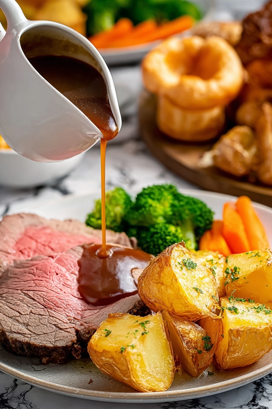 A dark plate holds one thick slice of cooked beef with a layer of pink inside and browned edges near the bottom left, while a rich, brown sauce is poured from a white gravy boat onto the center of the beef. Around the beef are several golden brown roasted potato pieces with a crispy texture, bright orange cooked carrot sticks, a golden popover with a light and puffy texture on top, some small green broccoli florets, and a white cauliflower piece with light brown edges toward the front right. In the background, there is a wooden board with a large roast and more golden potatoes, set on a white marbled surface, a navy blue cloth is folded close to the plate. The scene is bright and detailed, showing the textures clearly. Photo taken with an iphone --ar 4:5 --v 7