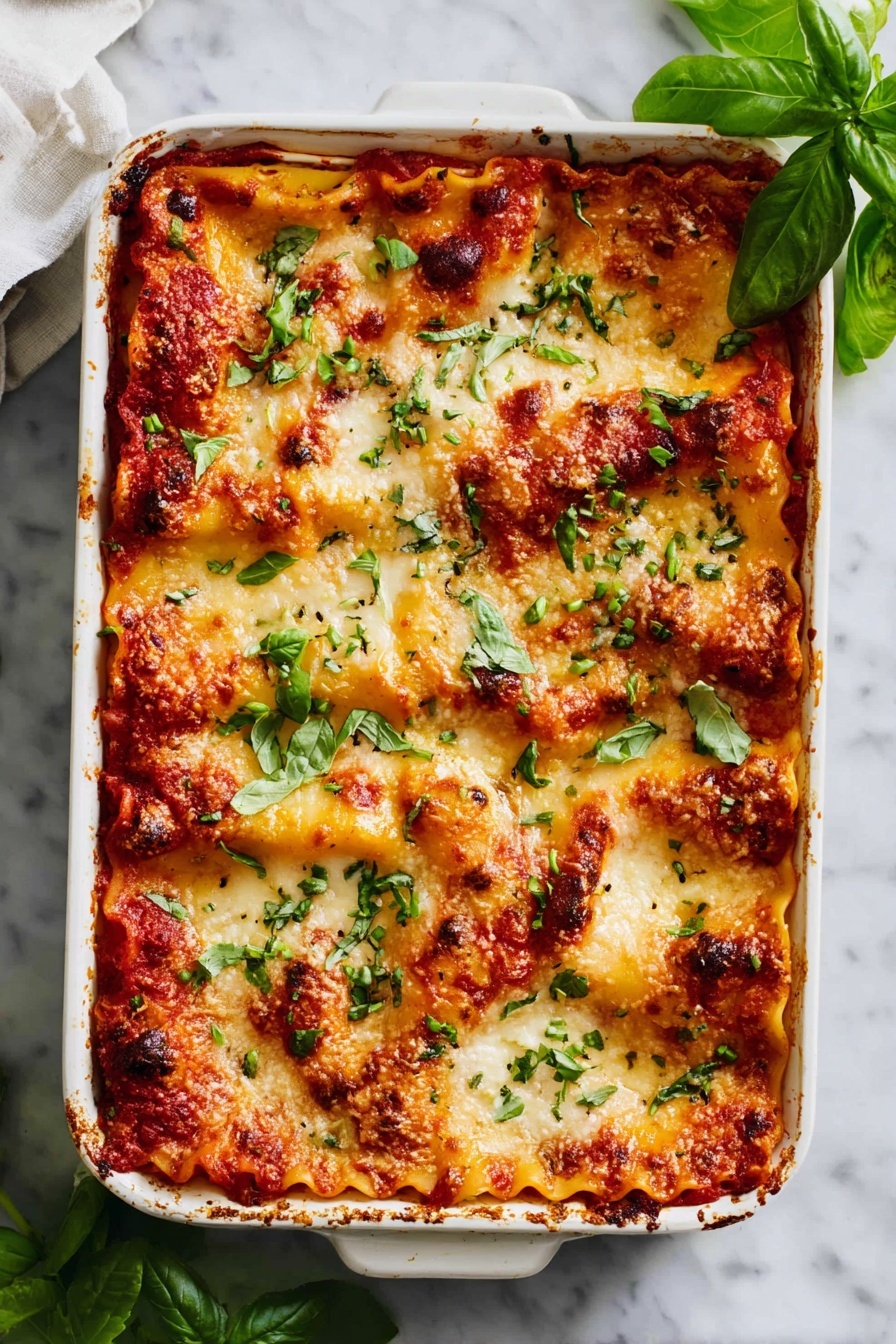 The image shows a white rectangular baking dish filled with a layered lasagna that has about four visible layers of pasta with melted golden cheese and rich red tomato sauce in between each layer. The top layer is entirely covered with browned, bubbling cheese that has a slightly crispy texture, dotted with fresh bright green basil leaves scattered on top. The dish is placed on a white marbled surface with a few extra basil sprigs around it, creating a fresh and inviting look. photo taken with an iphone --ar 4:5 --v 7