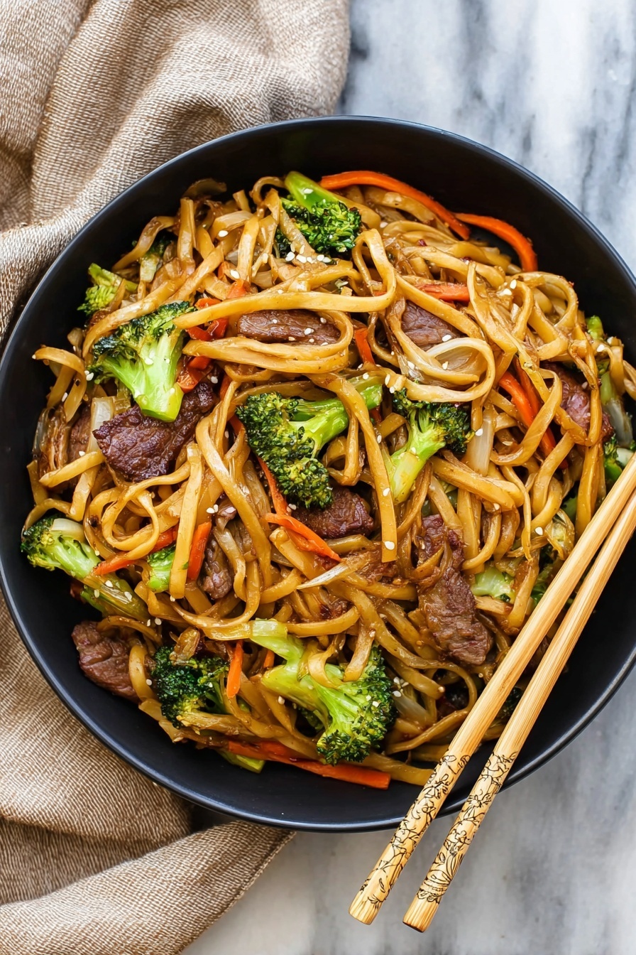 A black bowl filled with stir-fried noodles layered with dark brown grilled beef pieces, bright green broccoli florets, thin orange carrot strips, and light brown onion slices all mixed together with a shine of sauce, sprinkled lightly with white sesame seeds. The bowl sits on a white marbled surface with a beige linen cloth partially under it on the top left and a pair of light wooden chopsticks with carved patterns on the top right. Photo taken with an iphone --ar 4:5 --v 7