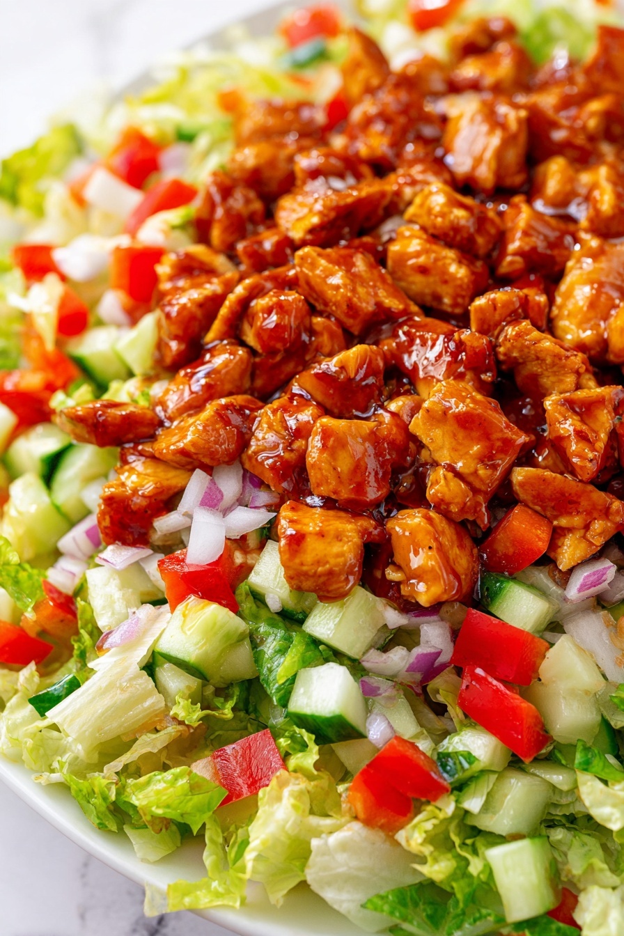 The dish shows a close-up of a salad on a white plate with a white marbled background. The bottom layer has bright green chopped lettuce with a light, crisp texture. Over the lettuce, there are small diced pieces of red bell pepper and white chopped onion spread evenly, adding red and white colors. There are also small cubes of green cucumber scattered throughout this layer. Finally, the top layer consists of chunks of chicken coated in a shiny reddish-brown sauce, giving the salad a rich, glazed look. Photo taken with an iphone --ar 2:3 --v 7 - Honey Hot Chicken Salad, spicy chicken salad, quick chicken salad recipe, sweet and spicy chicken salad, easy chicken salad ideas